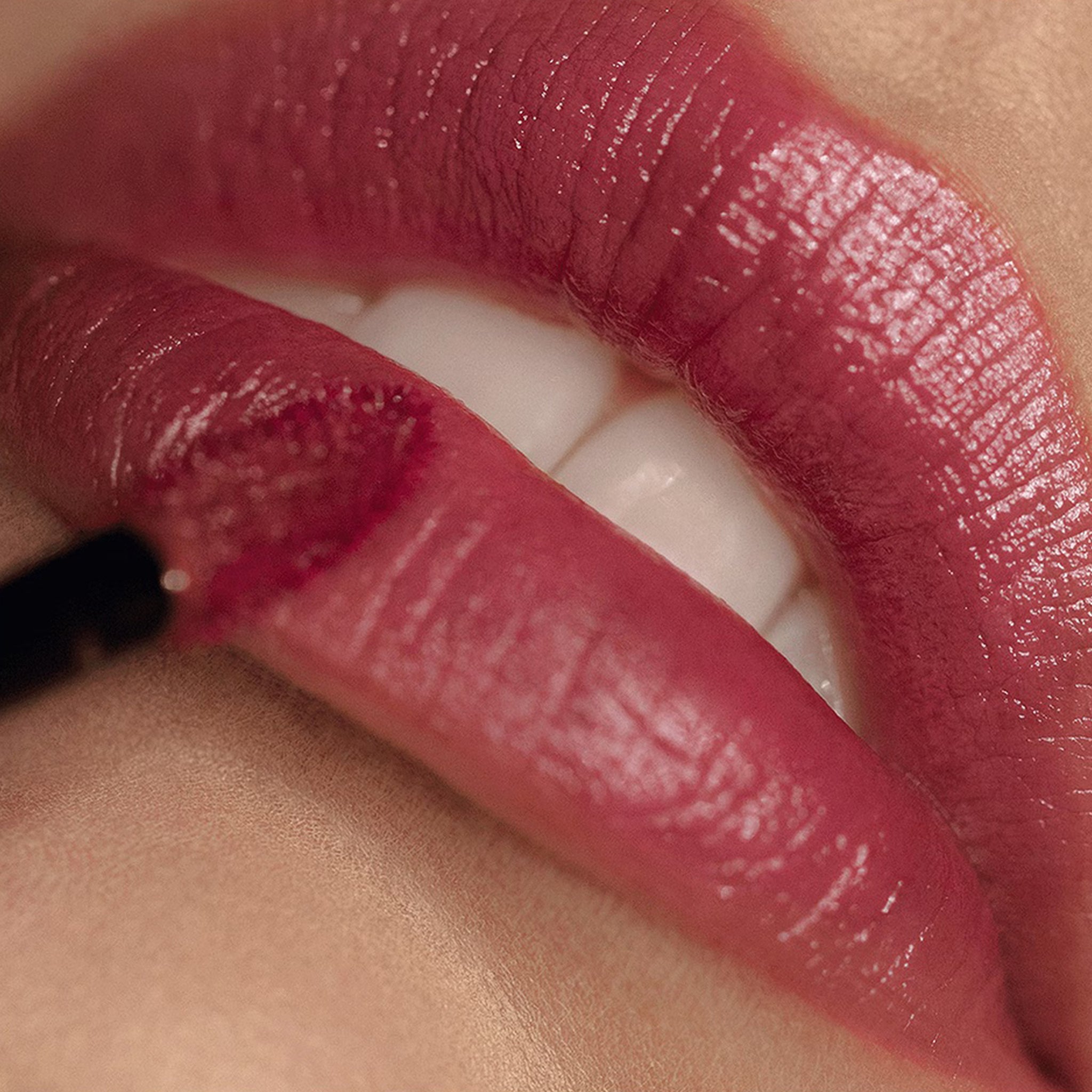 Close-up of a person applying pink lipstick with a brush.