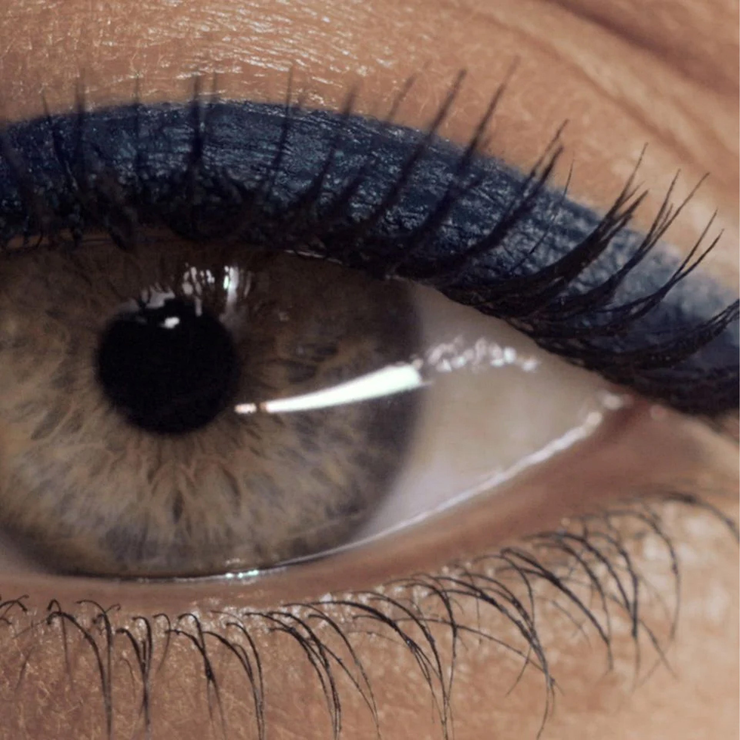 A very close up image of an eye with navy eyeliner applied to the eyelid.