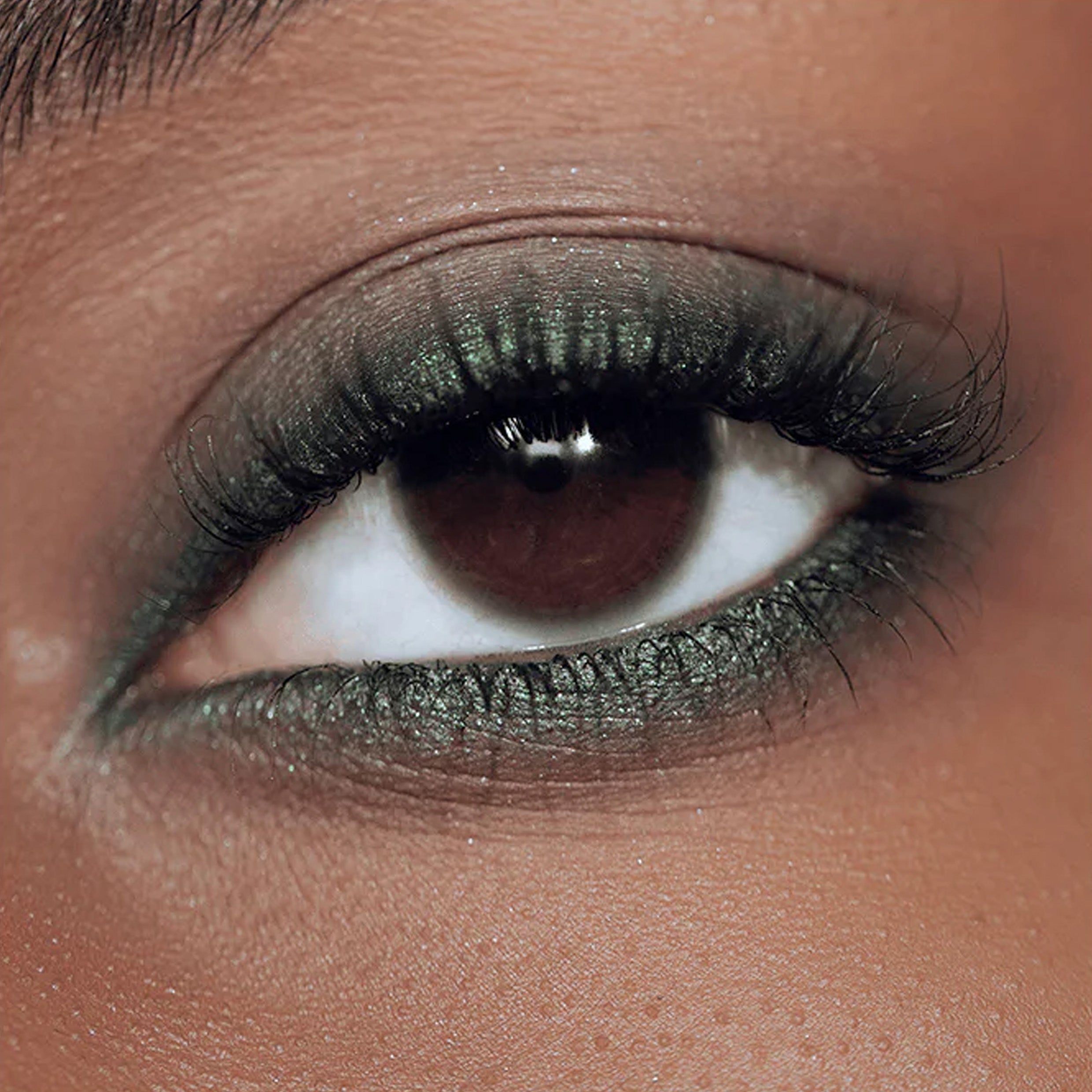A zoomed in image of an eye with green eyeliner applied to the eyelid.