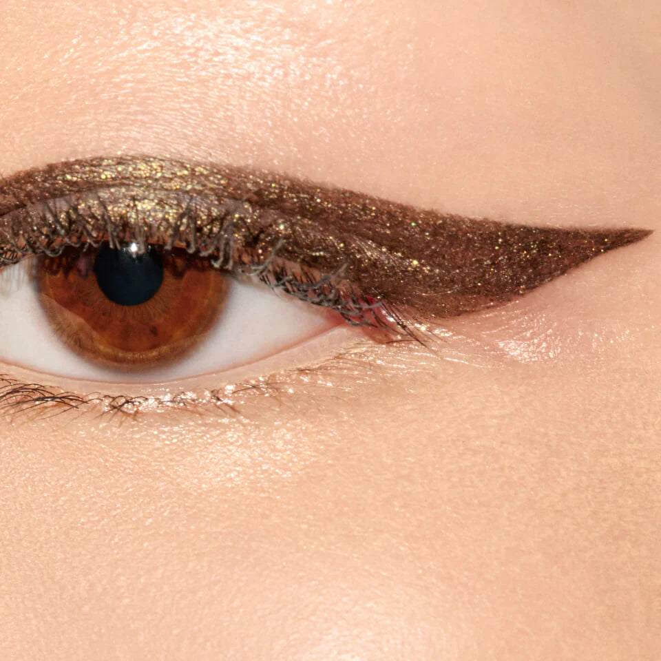 A close up image of an eye with gold brown eyeliner applied to the eyelid.