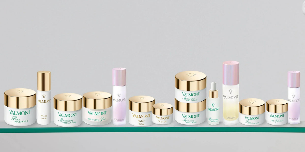 Valmont skincare jars and bottles with gold and pale pink details on a glass shelf