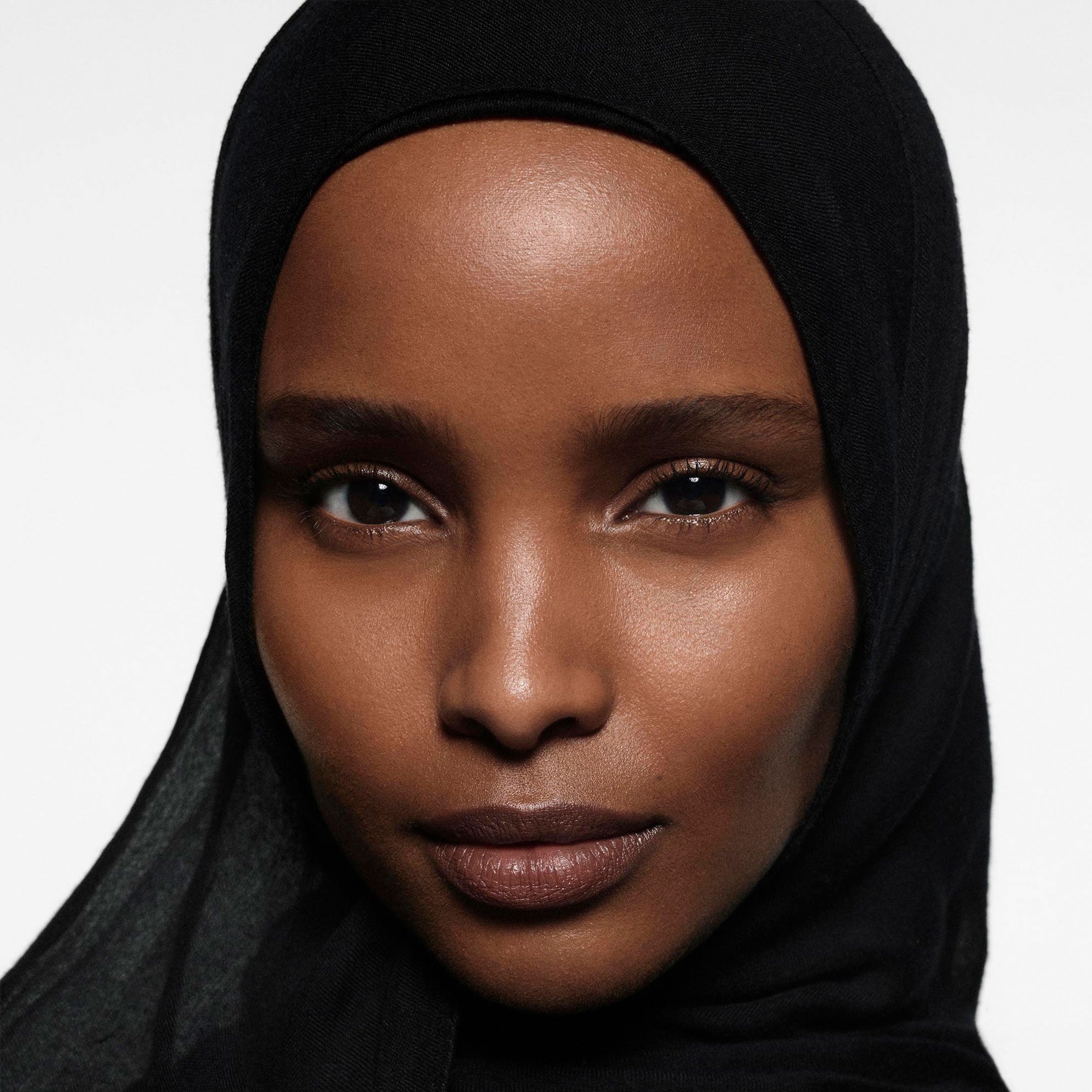 Woman wearing a black hijab against a white background