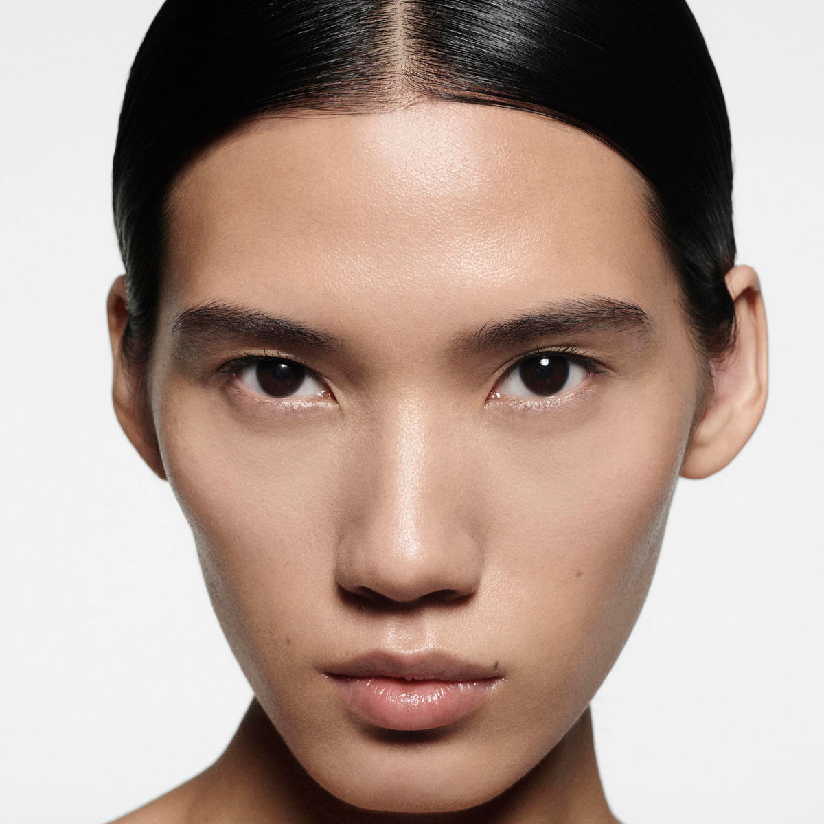 Close-up of a person with a neutral expression on a plain background