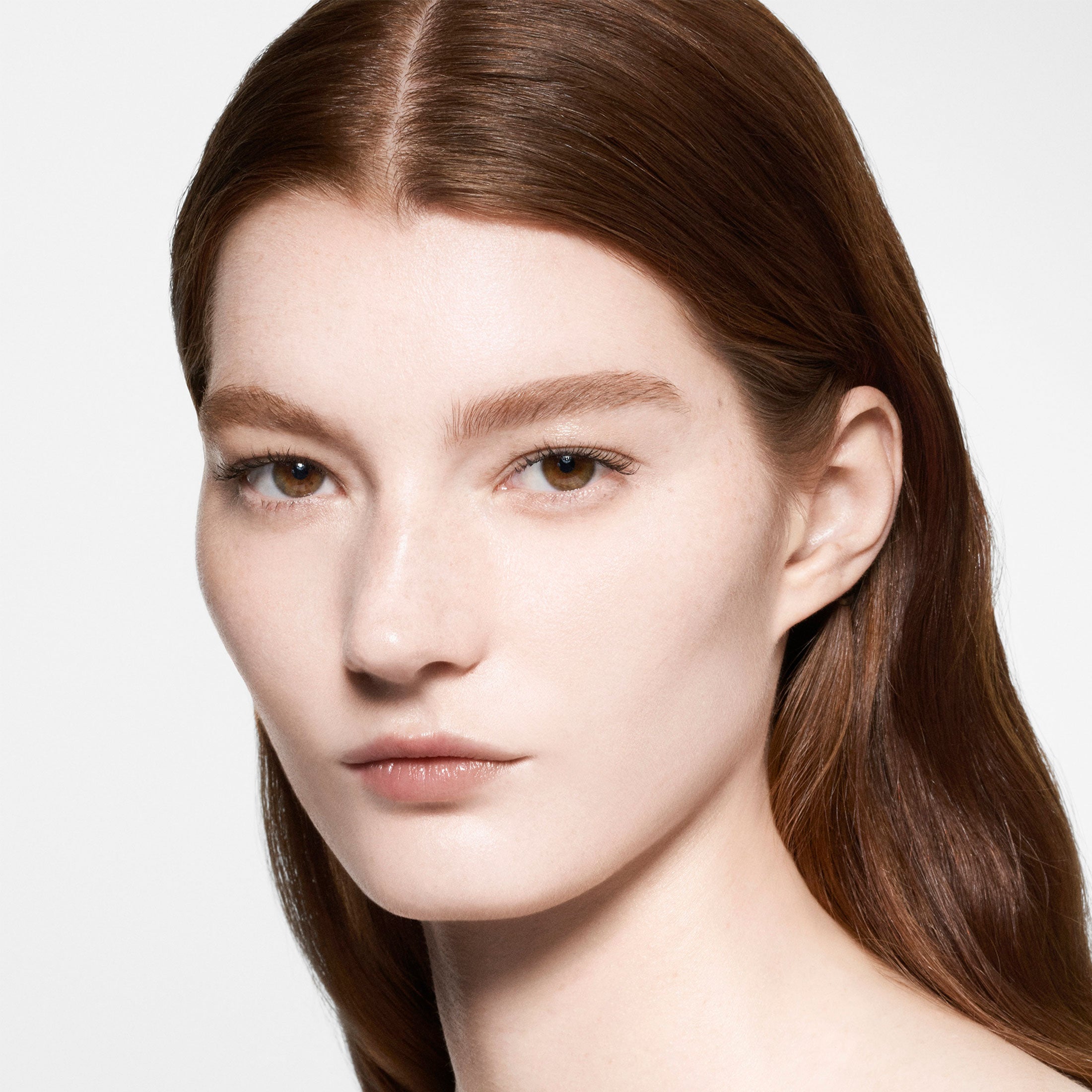 Close-up of a person with long brown hair on a plain background