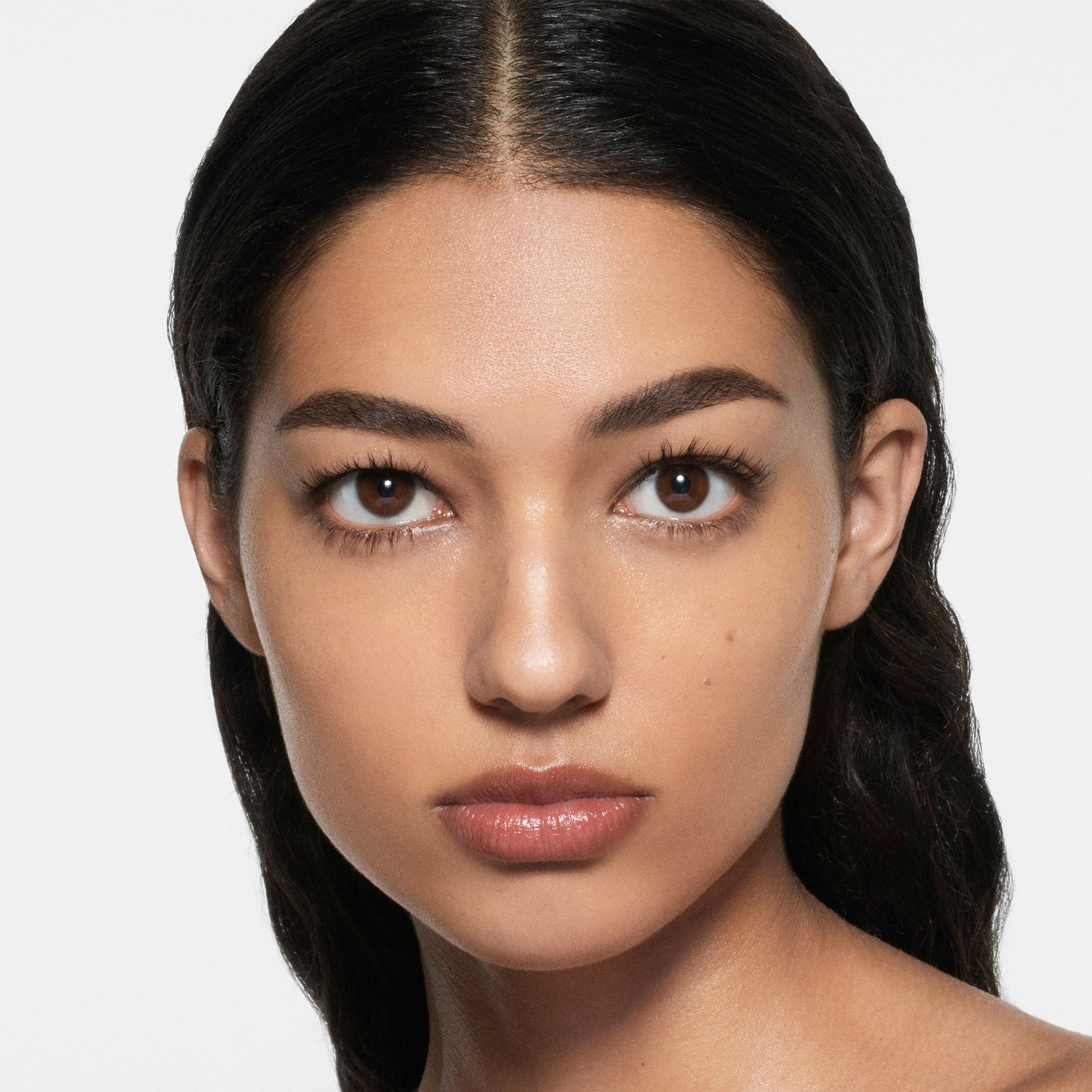 Close-up of a woman with dark hair and brown eyes on a white background