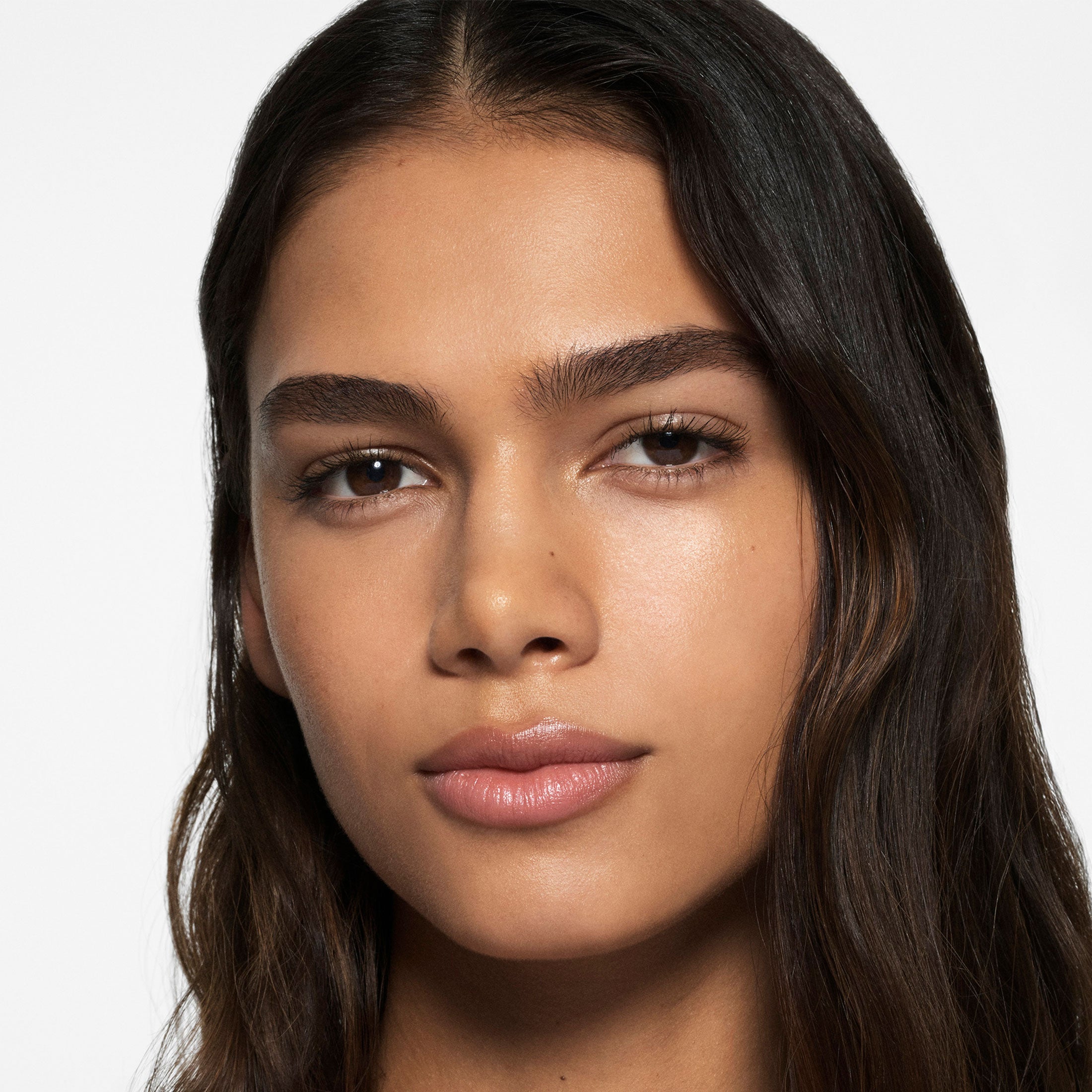 Close-up of a woman with long dark hair on a plain background