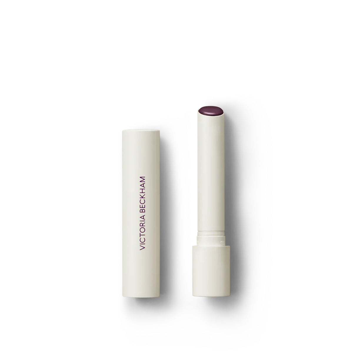Victoria Beckham Beauty Posh Balm in Cassis, a lip balm with a white bullet dispenser and a sheer blackberry color.