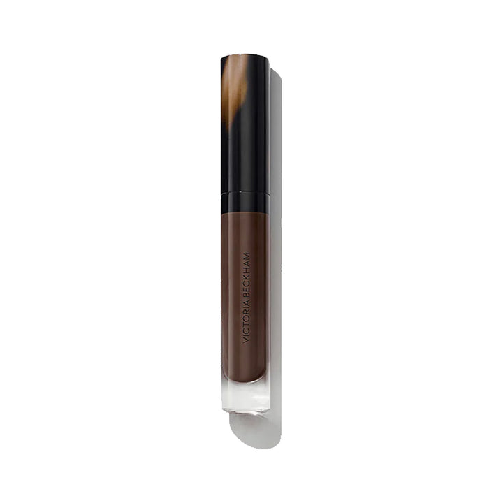 A tube of Victoria Beckham Beauty Posh Gloss in the shade 'Top Down', which is a chocolate berry color.