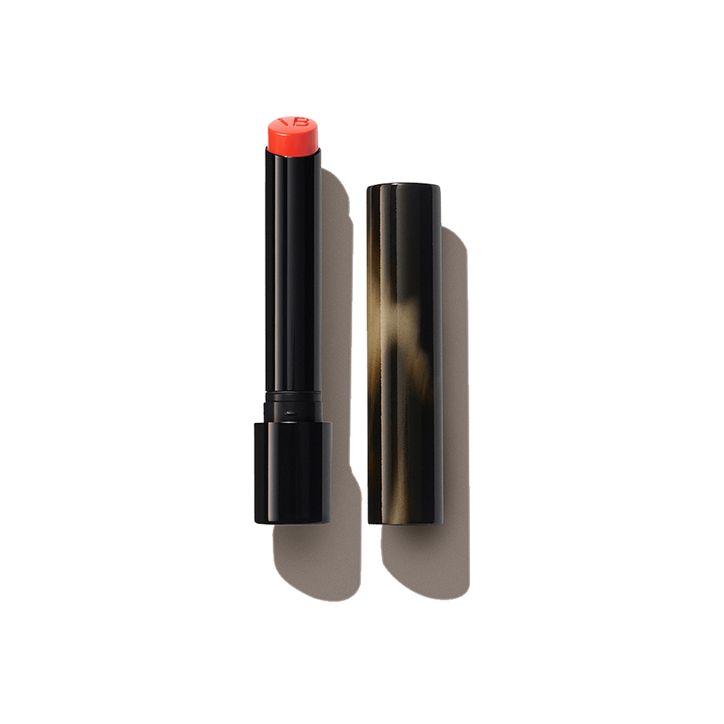 A Victoria Beckham Beauty Posh Lipstick in the shade Fire, with the cap removed, showing a bright red orange color.