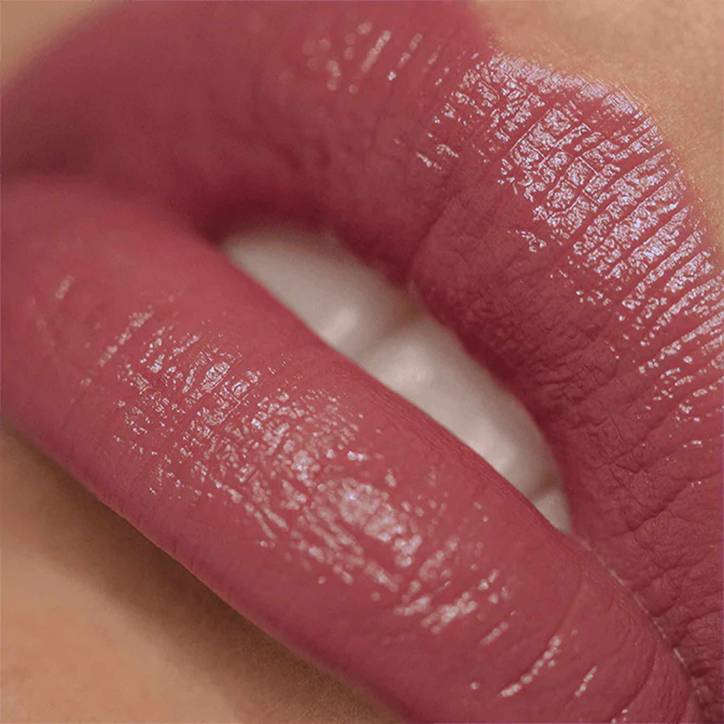 A very close up image of lips wearing lipstick in a berry pink colour.