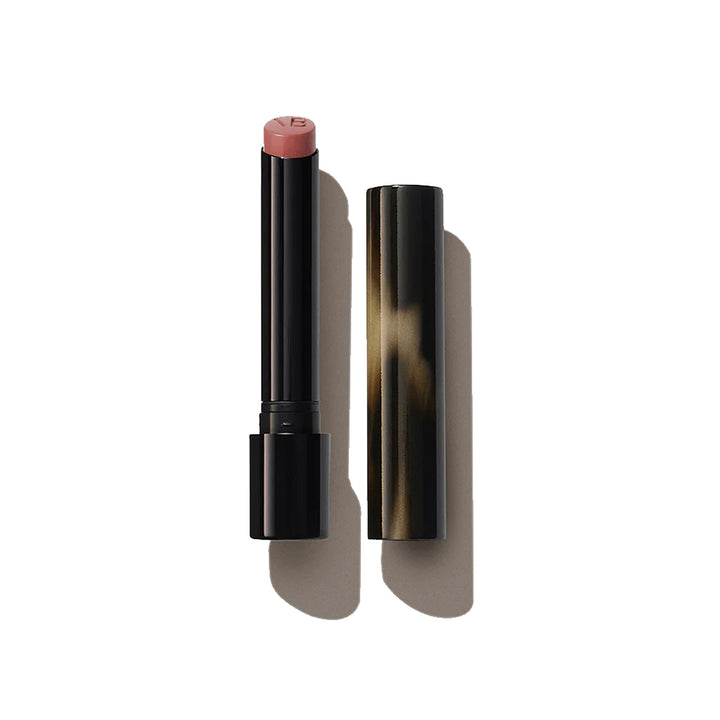 A Victoria Beckham Beauty Posh Lipstick in a neutral pink shade, with the twist-up design cap showing a patterned texture.