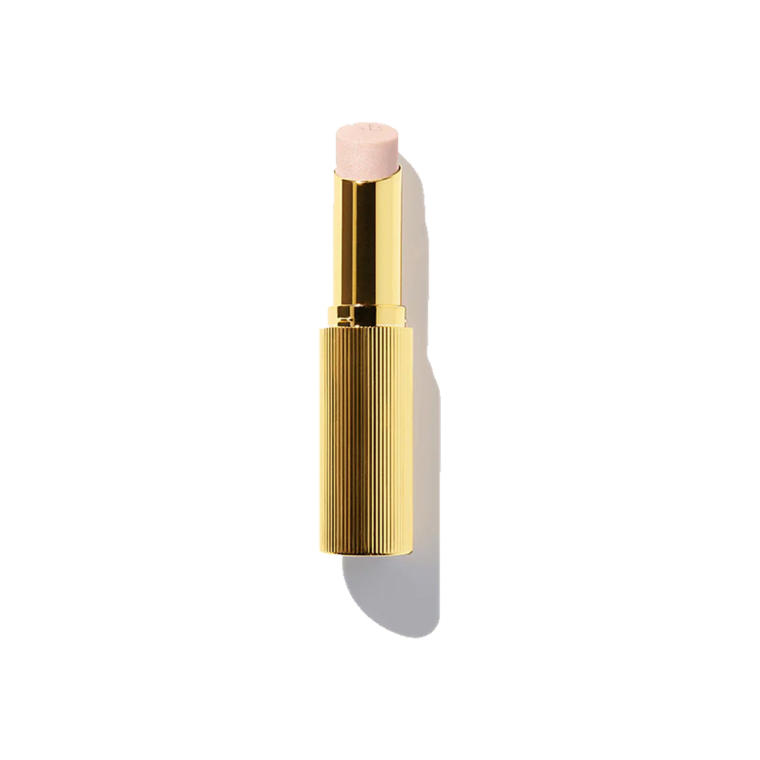 A gold-colored tube of Victoria Beckham Beauty Reflect Highlighter Stick with a pink-colored tip visible at the open end.