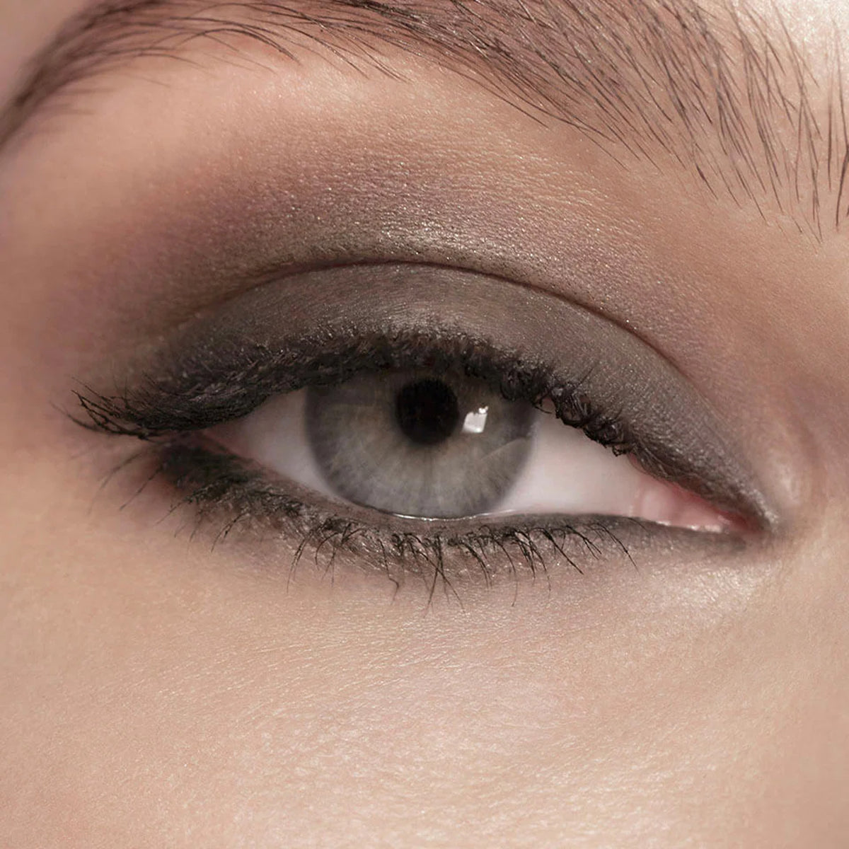 Zoomed in photo of an eye weith grey eyeliner applied to eyelid.