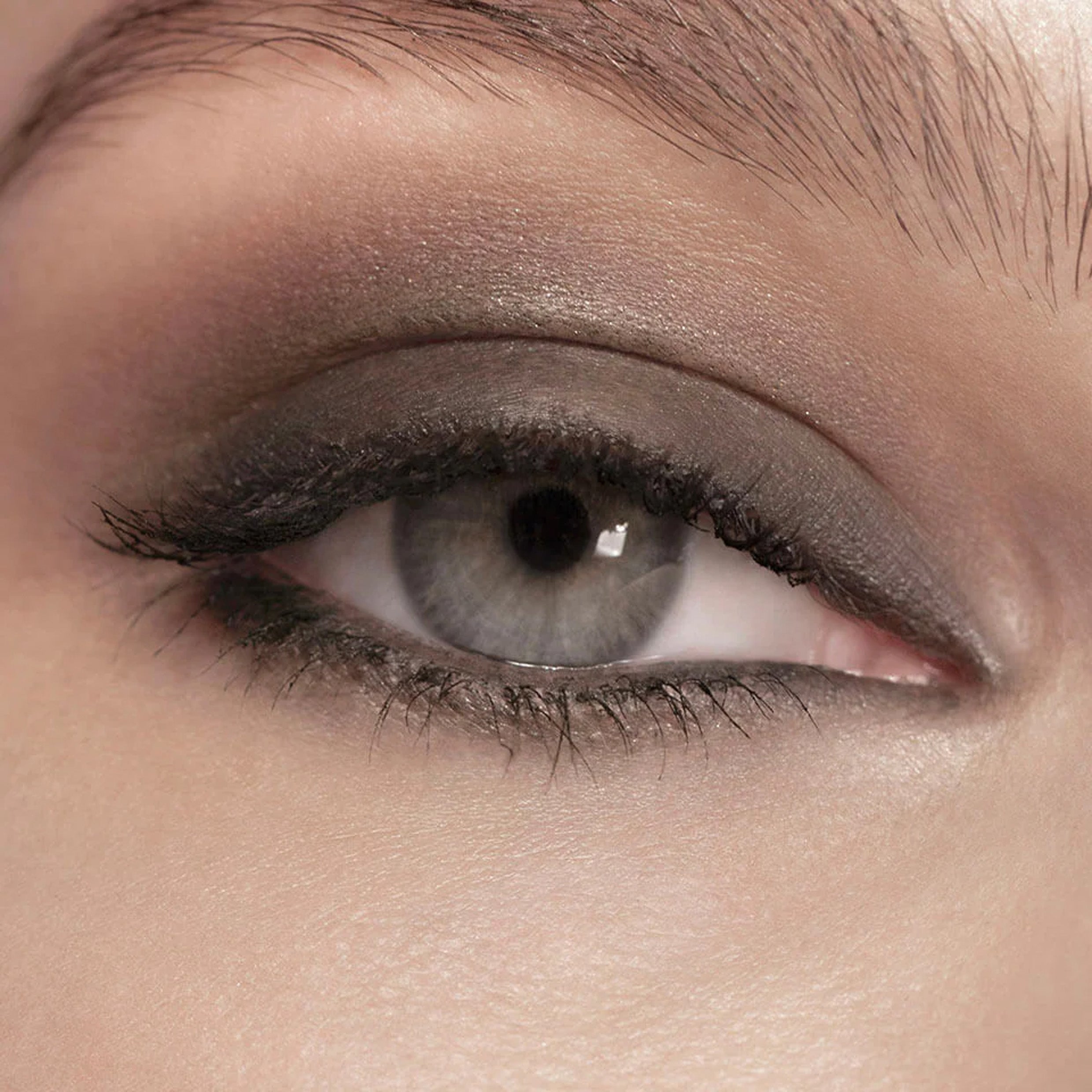 Zoomed in photo of an eye weith grey eyeliner applied to eyelid.