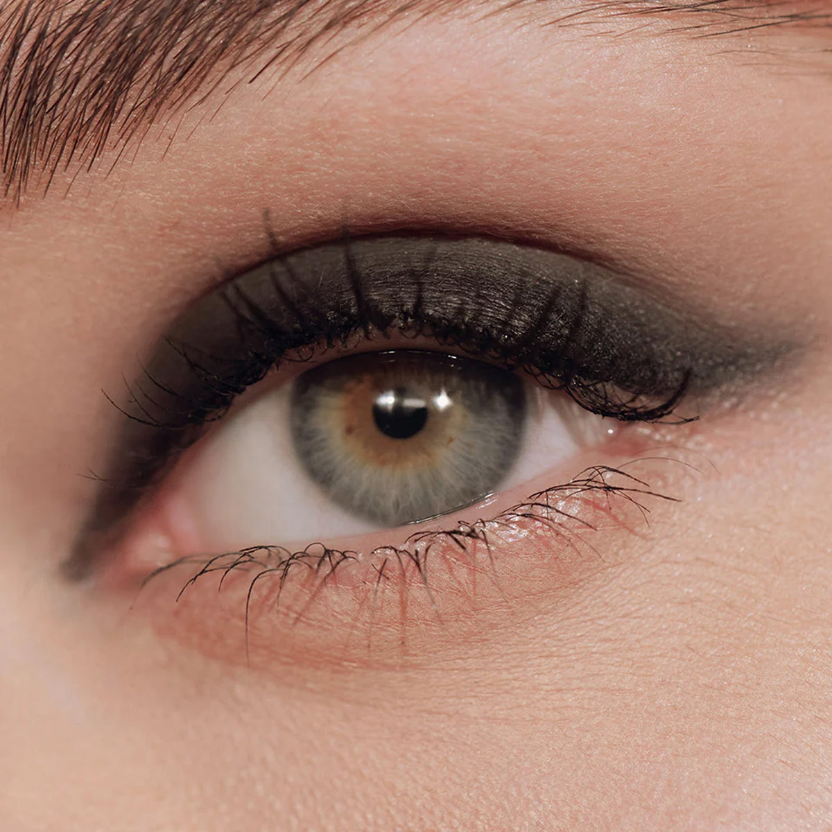 A close up image of an eye with black eyeliner applied to the eyelid.