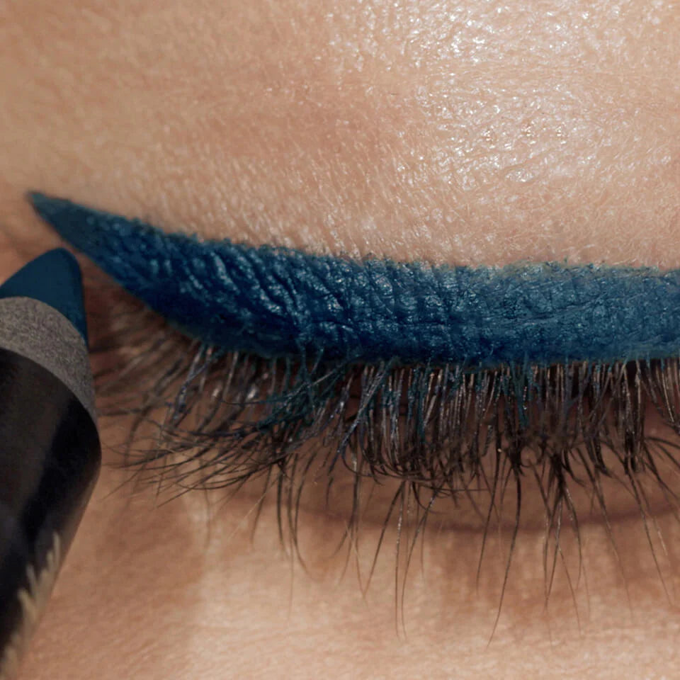 An eyelid showing a teal coloured eyeliner being applied with a pencil eyeliner.