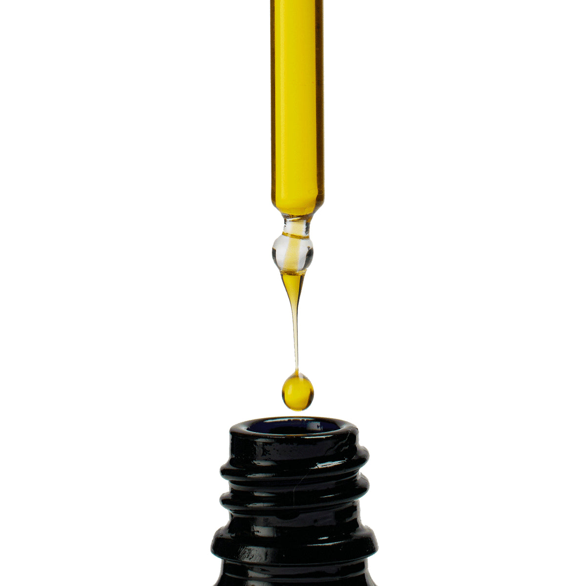 Yellow liquid being dripped from a dropper into a black container on a white background