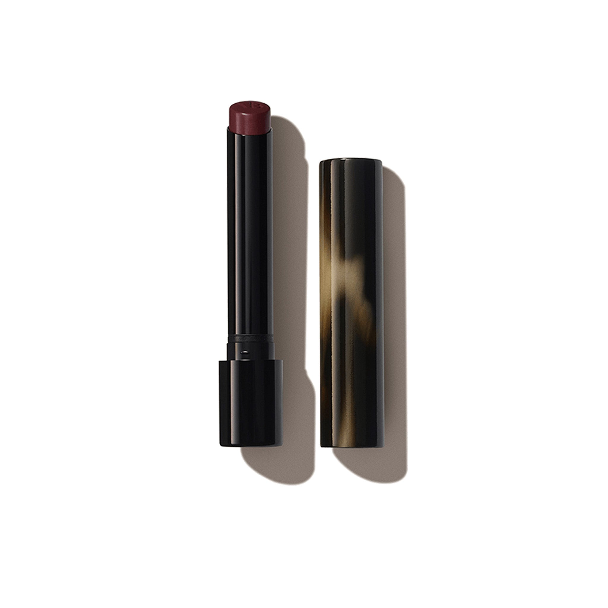 A Victoria Beckham Beauty Posh Lipstick in color 'Play', with the cap removed, revealing a rich plum berry shade.