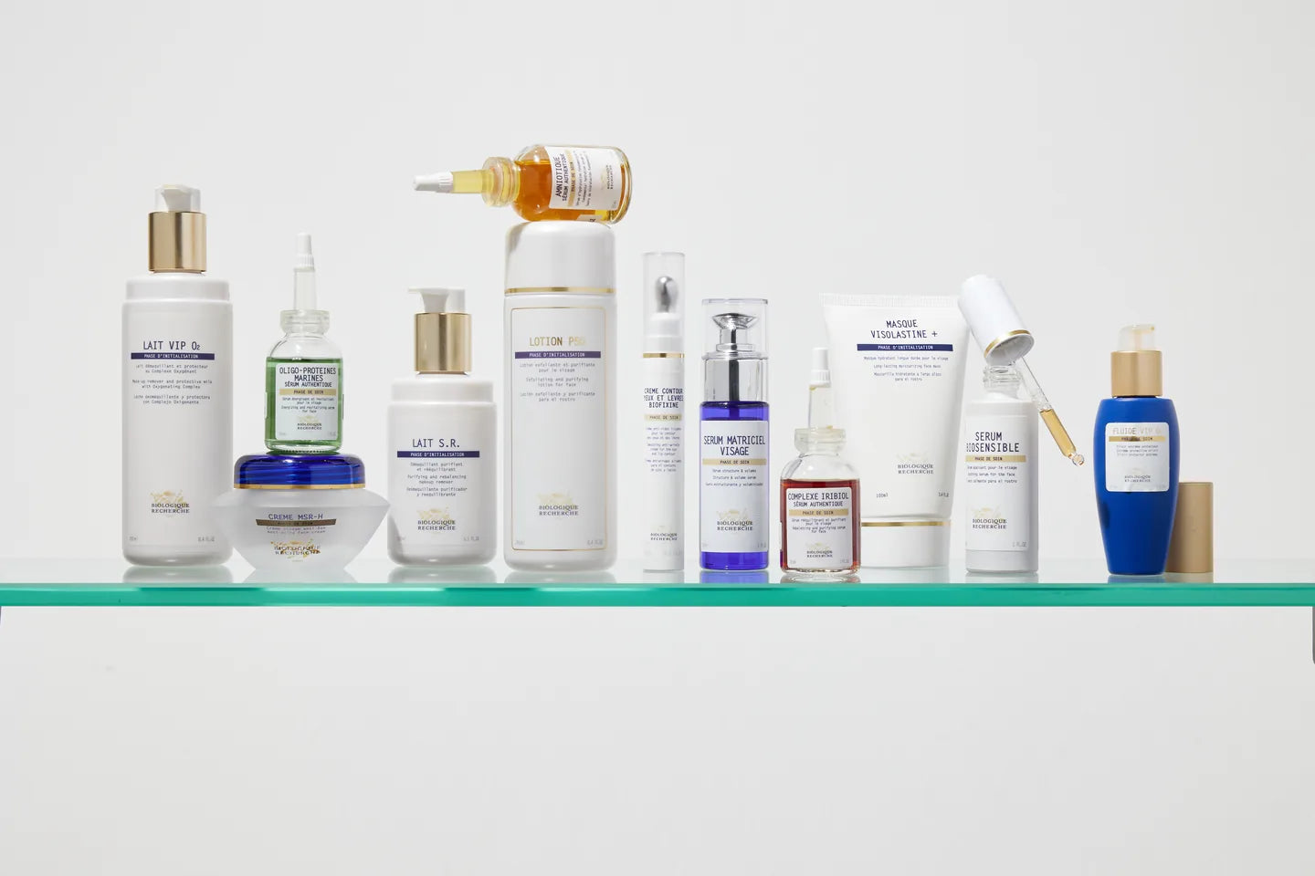 Biologique Recherche skincare in white, gold and blue bottles arranged on a glass shelf