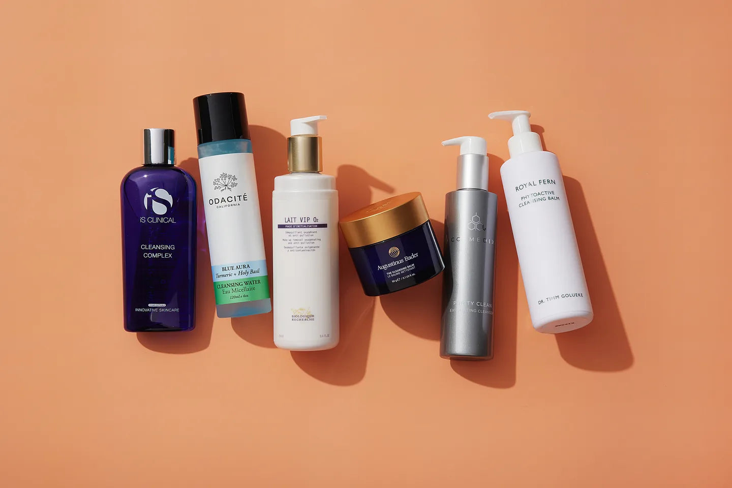 An archive arrangement of cleansing oils, milk, gel and balm bottles on a warm peach background