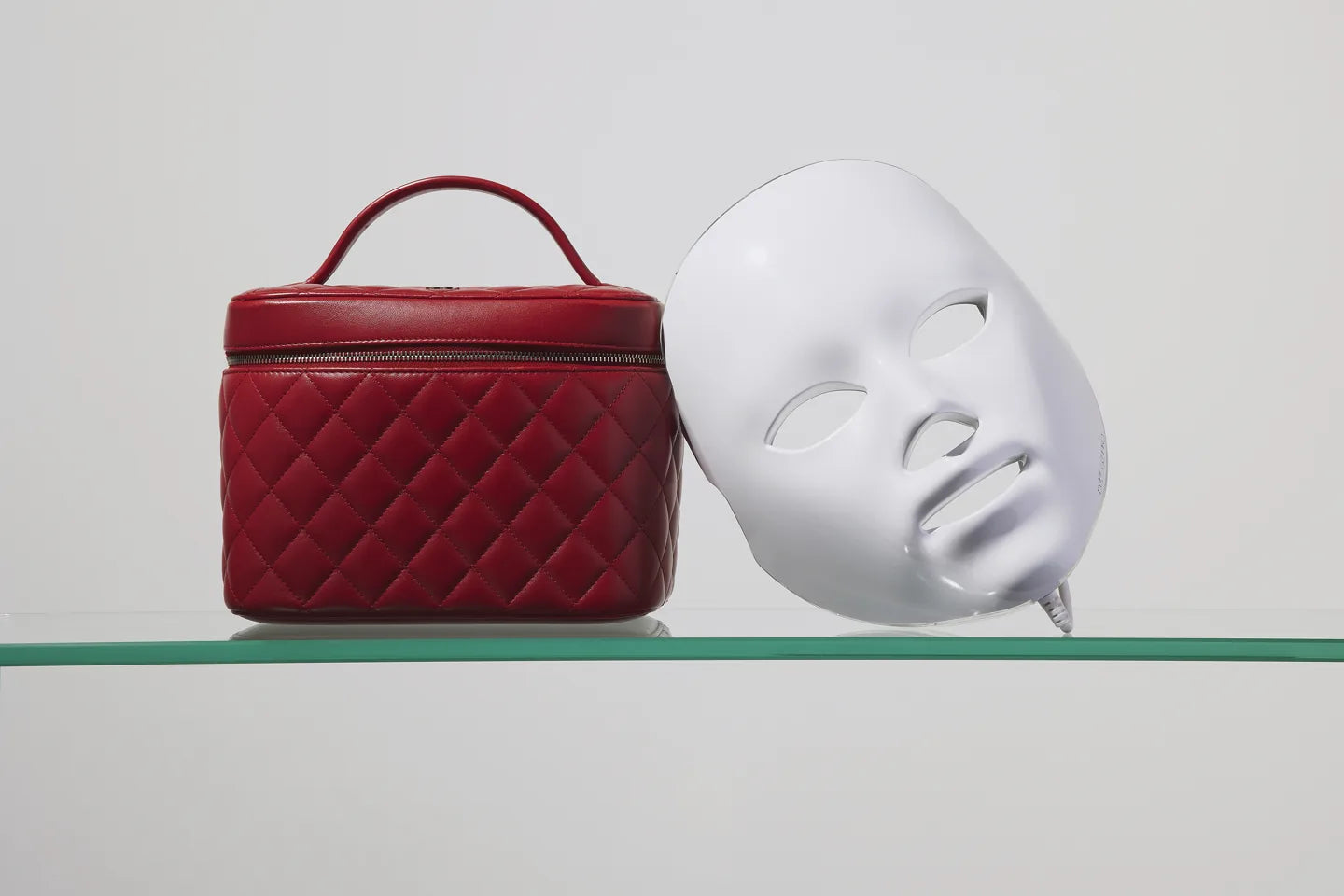 An archive photograph of a Déesse LED mask beside a red case